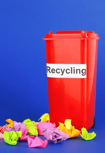 Papelera de reciclaje con papeles sobre fondo azul — Foto de Stock