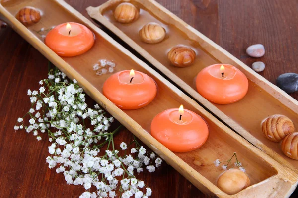 Beautiful candles in water on wooden table close-up — Stock Photo, Image