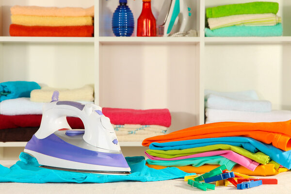 Одежда и утюг на столе на полках

