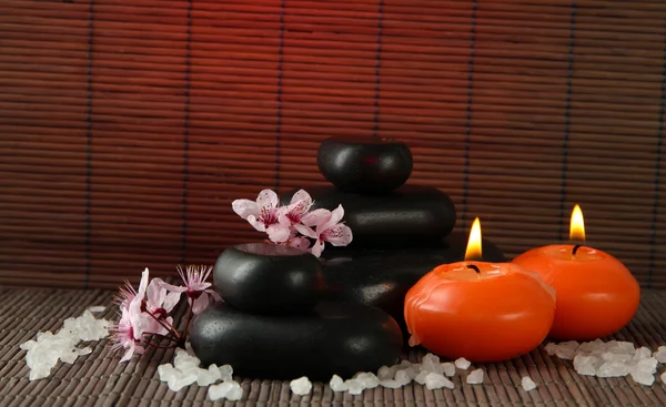 Spa stones with flowers and candles on bamboo background — Stock Photo, Image