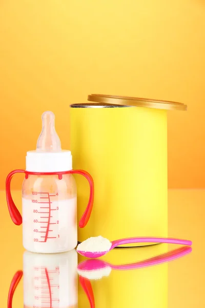 Bottle with milk and food for babies on orange background — Stock Photo, Image