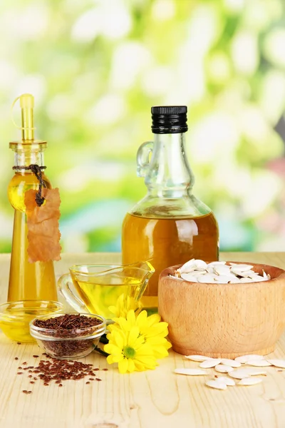 Useful linseed oil and pumpkin seed oil on wooden table on natural background — Stock Photo, Image