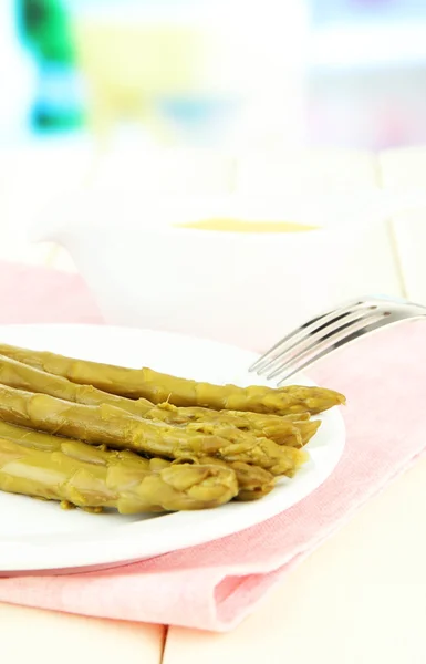 Asperges op plaat, op houten tafel op lichte achtergrond — Stockfoto