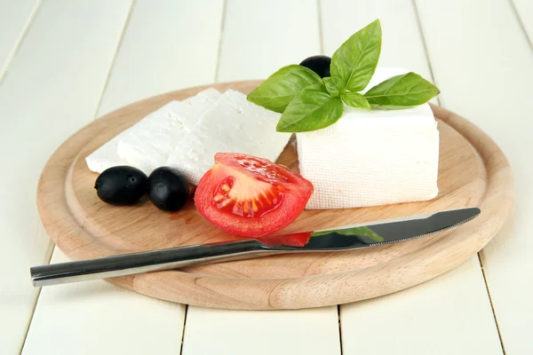 Queijo de ovelha, azeitonas pretas, tomate vermelho com manjericão sobre tábua de corte, isolado sobre branco — Fotografia de Stock