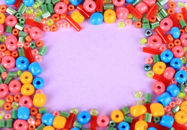 Different colorful beads on purple background — Stock Photo, Image