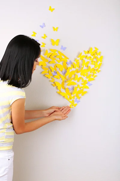 Девушка возле бумажных бабочек летит на стене — стоковое фото