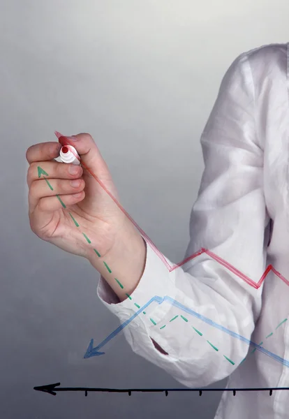 Woman paints graphic on glass on grey background — Stock Photo, Image