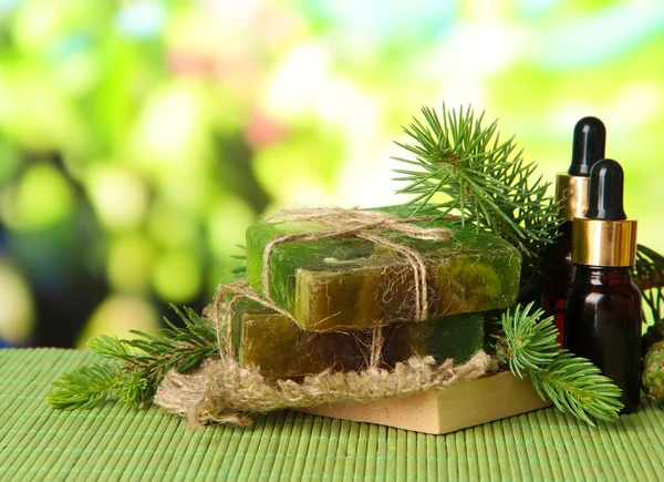 Hand-made soap and bottles of fir tree oil on bamboo mat — Stock Photo, Image