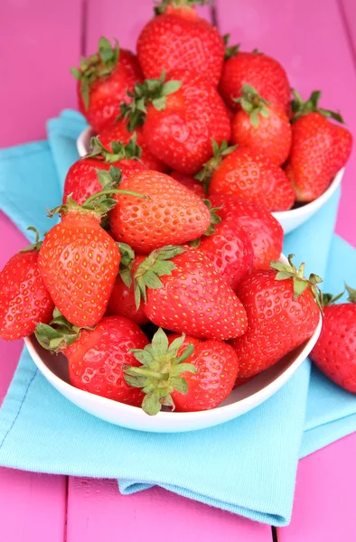 Verse aardbeien in kom op roze houten achtergrond — Stockfoto