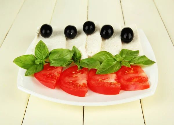 Formaggio di latte di pecora, con basilico e pomodoro su sfondo di legno di colore — Foto Stock