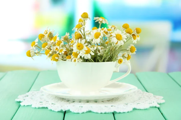 在明亮的背景上的杯子，洋甘菊的花束 — 图库照片