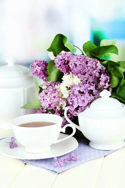 Composição com belas flores lilás, serviço de chá na mesa de madeira no fundo brilhante — Fotografia de Stock