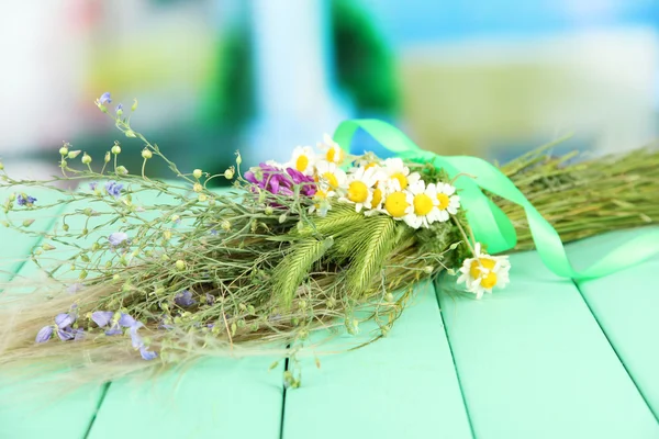Bouquet of wild flowers and herbs, on wooden table on bright background — Stock Photo, Image