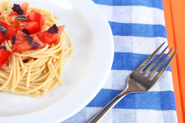 Spaghetti with tomatoes and basil leaves on wooden background — Stock Photo, Image