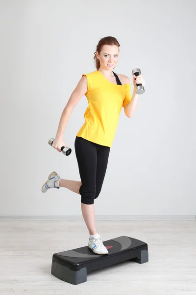 Mooie jonge vrouw oefeningen met dumbbell op stepper — Stockfoto