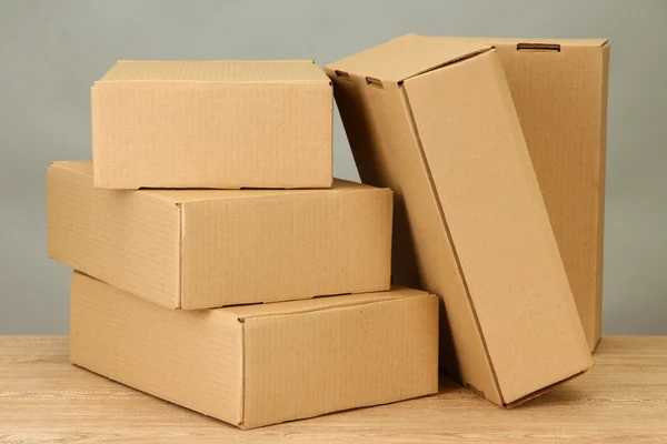 Parcels boxes on wooden table, on grey background Royalty Free Stock Images