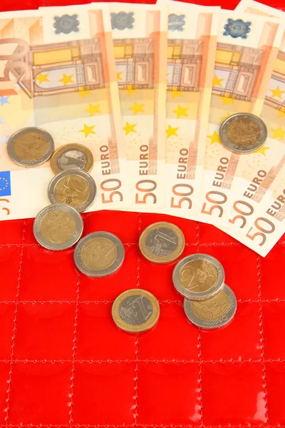 Euro banknotes and euro cents on red background — Stock Photo, Image