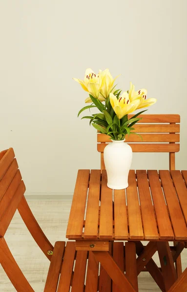 Indah bunga lili oranye di vas di atas meja kayu — Stok Foto