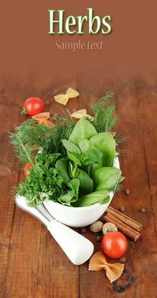 Herbs and spices in ceramic mortar, on wooden background — Stock Photo, Image