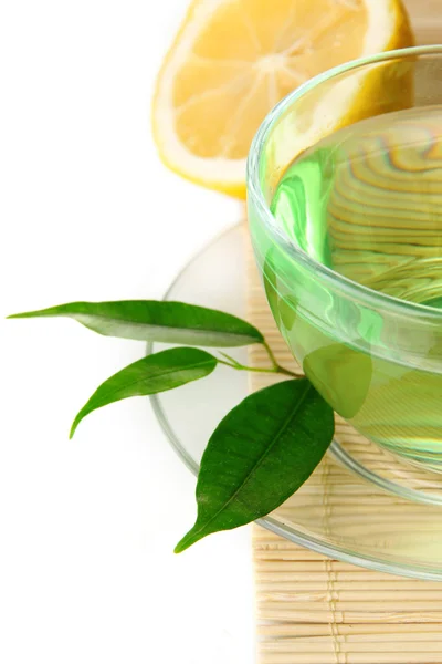Tasse transparente de thé vert au citron sur tapis de bambou, isolée sur blanc — Photo