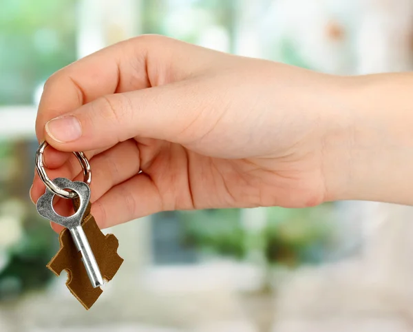 Nyckel med läder prydnadssak i handen på fönsterbakgrund — Stockfoto
