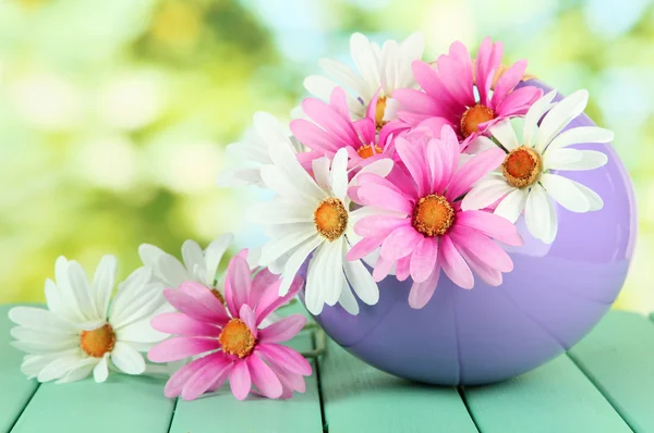 Pot with flowers on a wooden table on the nature background