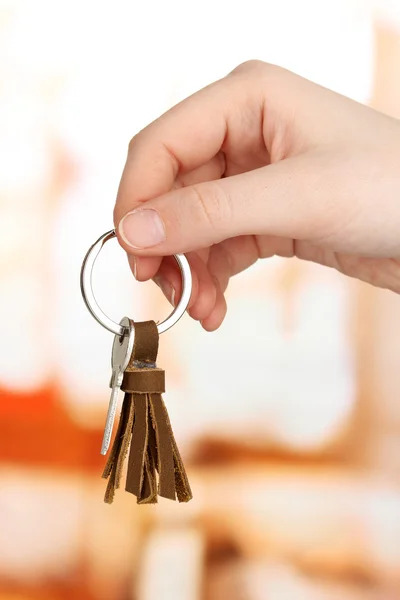 Key with leather trinket in hand on bright background — Stock Photo, Image