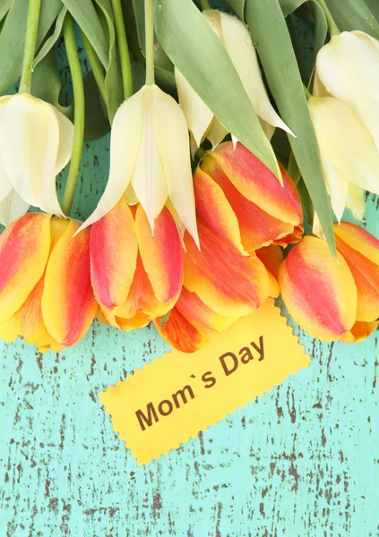 Beautiful white and orange tulips on color wooden background — Stock Photo, Image