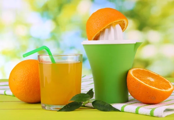 Citrus press, glass of juice and ripe oranges on white wooden table — Stock Photo, Image