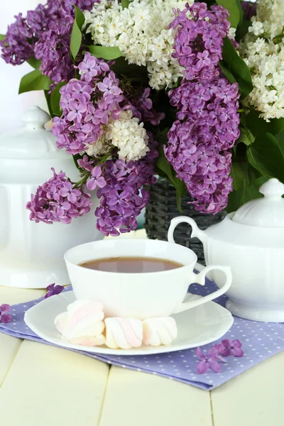 Sammansättning med vackra lila blommor, te service på träbord på ljus bakgrund — Stockfoto