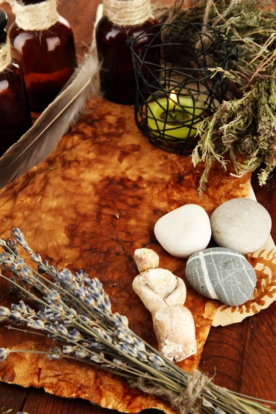 Composition with old papers, herbs, stones and bottles with symbols on wooden background — Stock Photo, Image