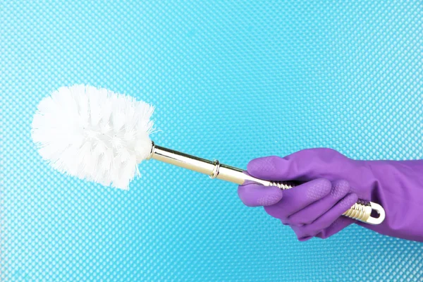 Brosse de toilette à la main sur fond bleu — Photo