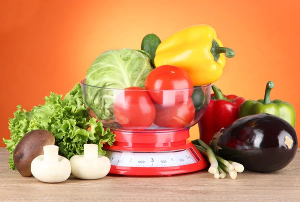 Verse groenten in schalen op tafel op oranje achtergrond — Stockfoto