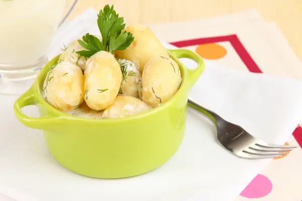 Jeunes pommes de terre tendres à la crème sure et aux herbes dans une casserole sur une table en bois close-up — Photo