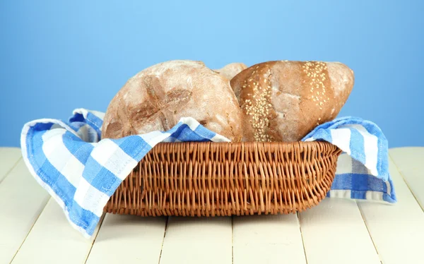 Brot im Weidenkorb, auf Holztisch, auf farbigem Hintergrund — Stockfoto