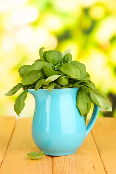 Fresh herb in pitcher on wooden table on natural background — Stock Photo, Image