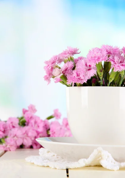 Viele kleine rosa Nelken in Tasse auf Holztisch auf Fensterhintergrund — Stockfoto