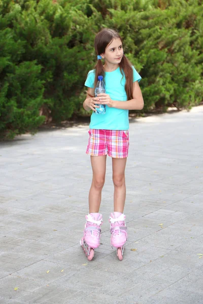 Niña en patines bebiendo agua en el parque —  Fotos de Stock