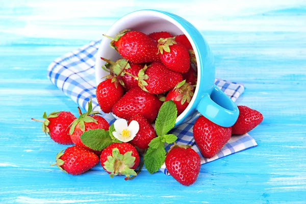 Ripe sweet strawberries in cup on blue wooden table — Stock Photo, Image