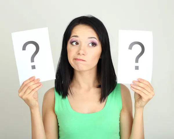 Woman with question marks on grey background — Stock Photo, Image