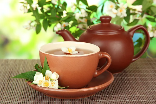 Cup of tea with jasmine, on bamboo mat, on bright background — Stock Photo, Image