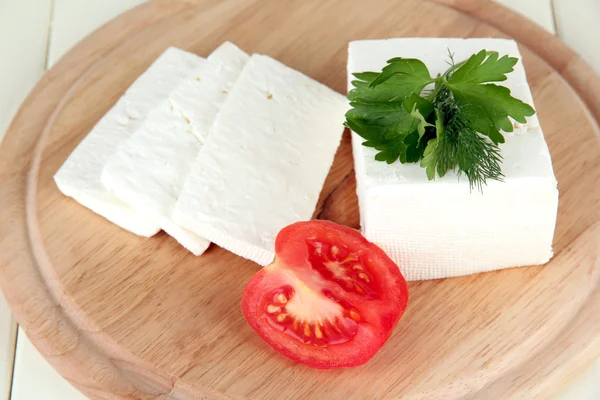 Сыр из овечьего молока, красный помидор с петрушкой и укроп на разделочной доске, изолированный на белом — стоковое фото