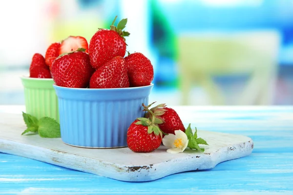 Reife süße Erdbeeren in Schalen auf blauem Holztisch — Stockfoto