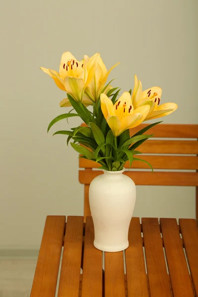 Beautiful orange lilies in vase on wooden table — Stock Photo, Image