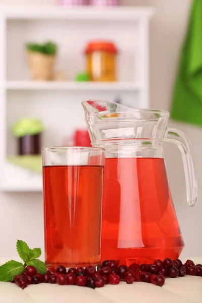 Tillbringare och ett glas tranbärsjuice med röda tranbär på bord — Stockfoto