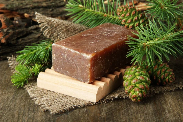 Jabón hecho a mano y conos de pino verde sobre fondo de madera — Foto de Stock