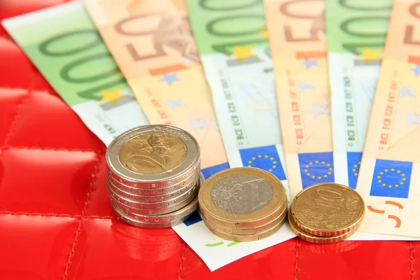 Eurobankovky a euro centů na červeném pozadí — Stock fotografie