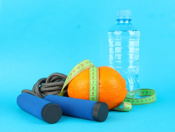 Laranja com fita métrica, pulando corda e garrafa de água, no fundo de cor — Fotografia de Stock