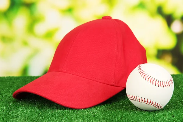 Red peaked cap on grass on natural background