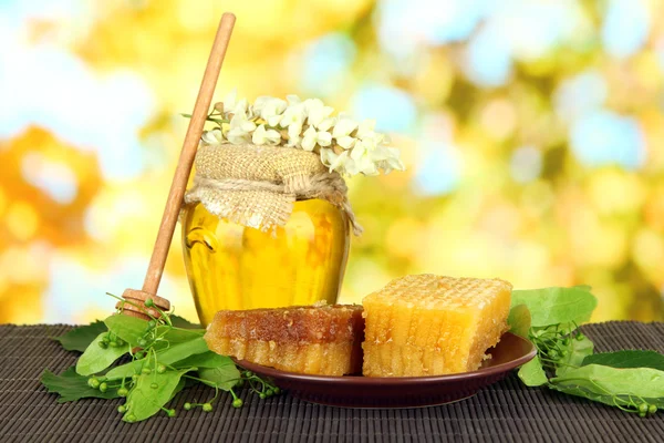 Frasco de mel com flores de limão, acácia na esteira de bambu a cores no fundo brilhante — Fotografia de Stock